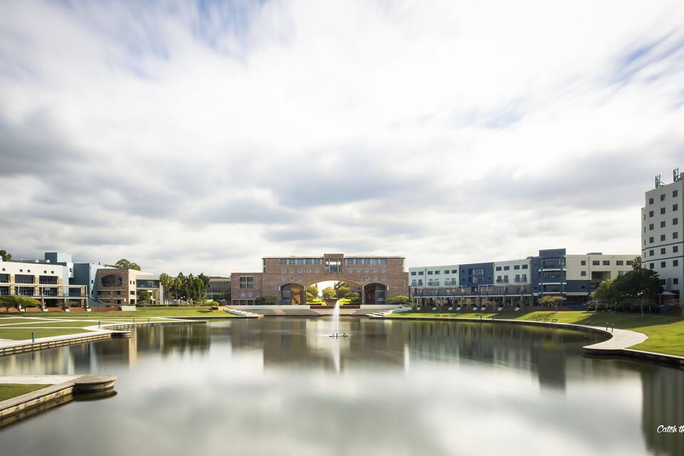 A modern building complex with a central courtyard and a reflective water feature.