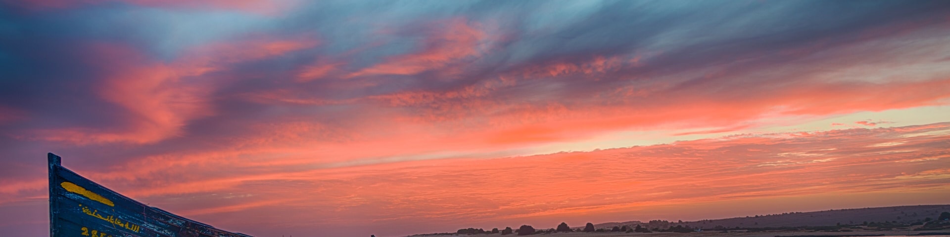 Deux bateaux sur une plage de sable, avec un ciel au coucher du soleil.