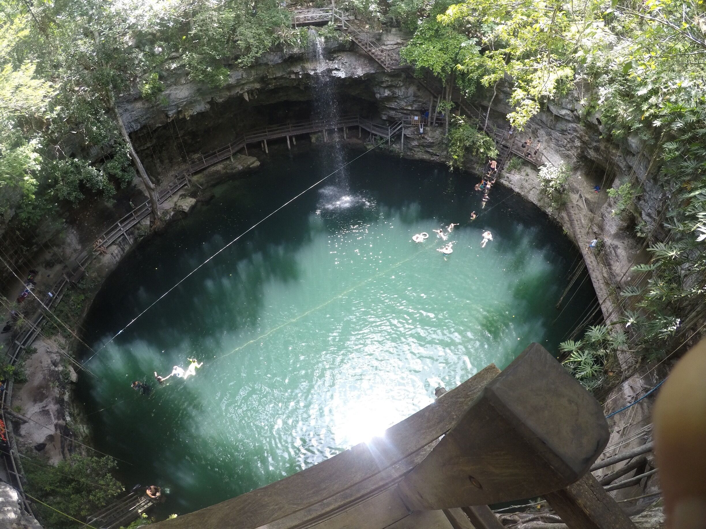 A circular natural pool surrounded by rocky cliffs and dense foliage.