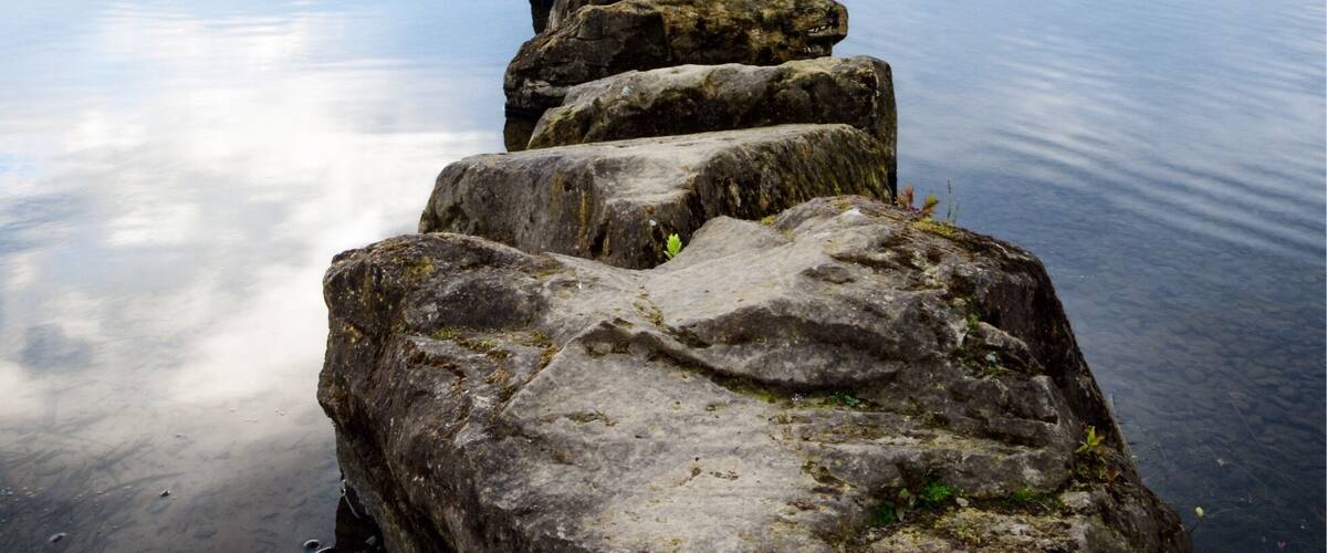 A stone pier extending into calm water under a cloudy sky.