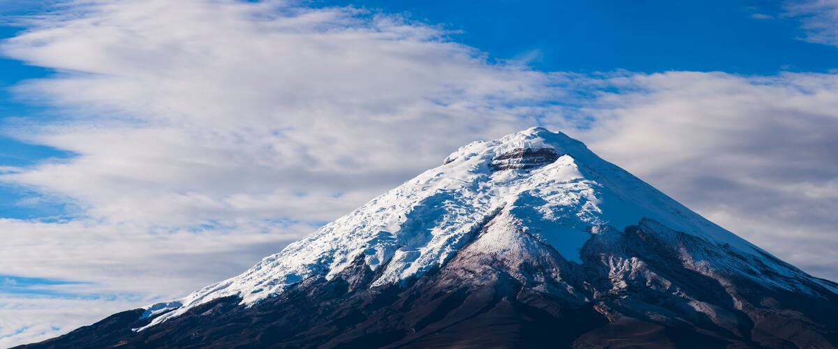 A snow-covered mountain peak under a partly cloudy sky.