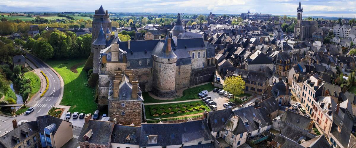 A historic town with a prominent castle, narrow streets, and surrounding greenery.