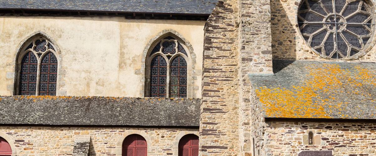A historic stone building with arched windows and a large circular stained glass window.