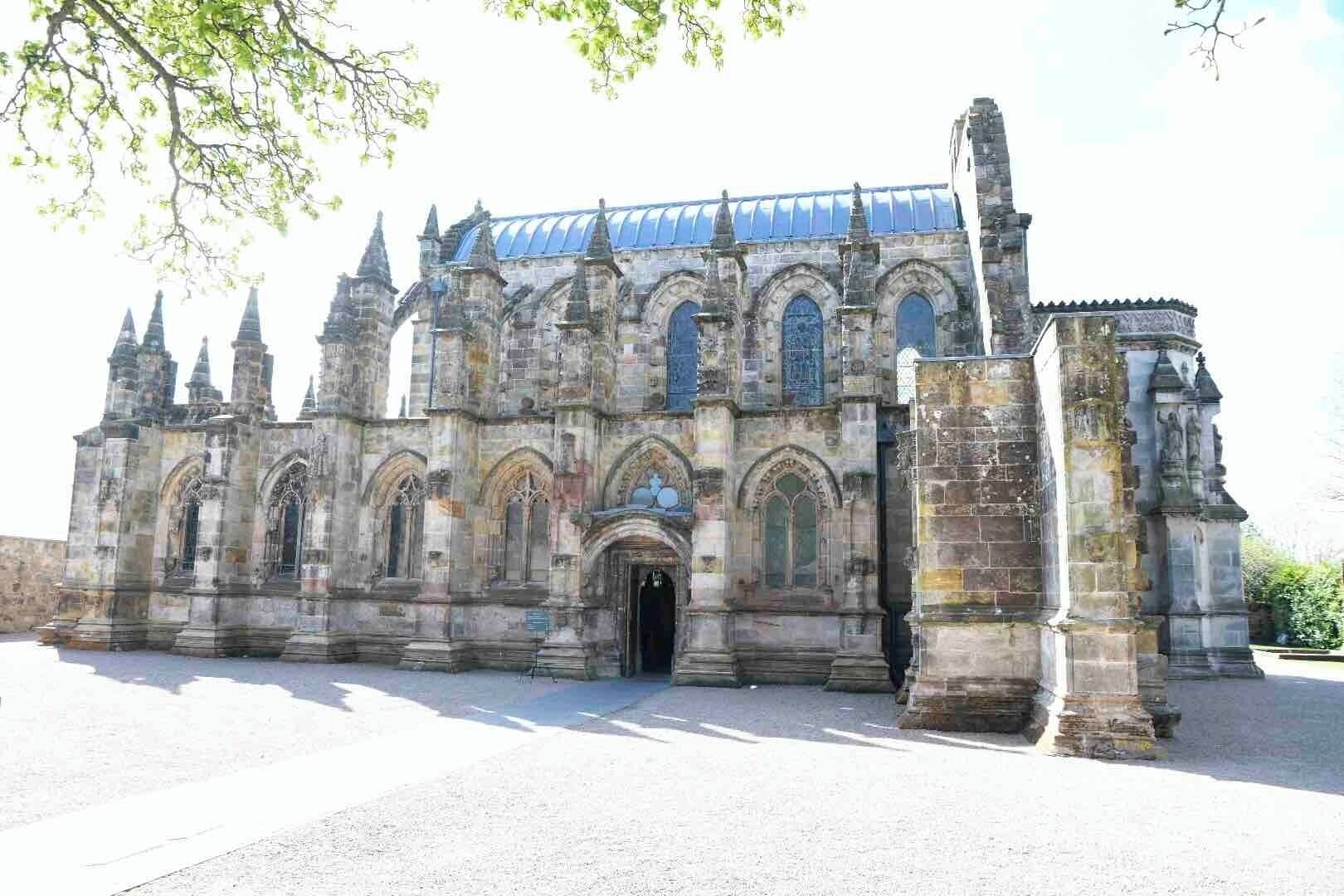 A historic cathedral with Gothic architecture, featuring pointed arches, a large rose window, and a blue-tiled roof.
