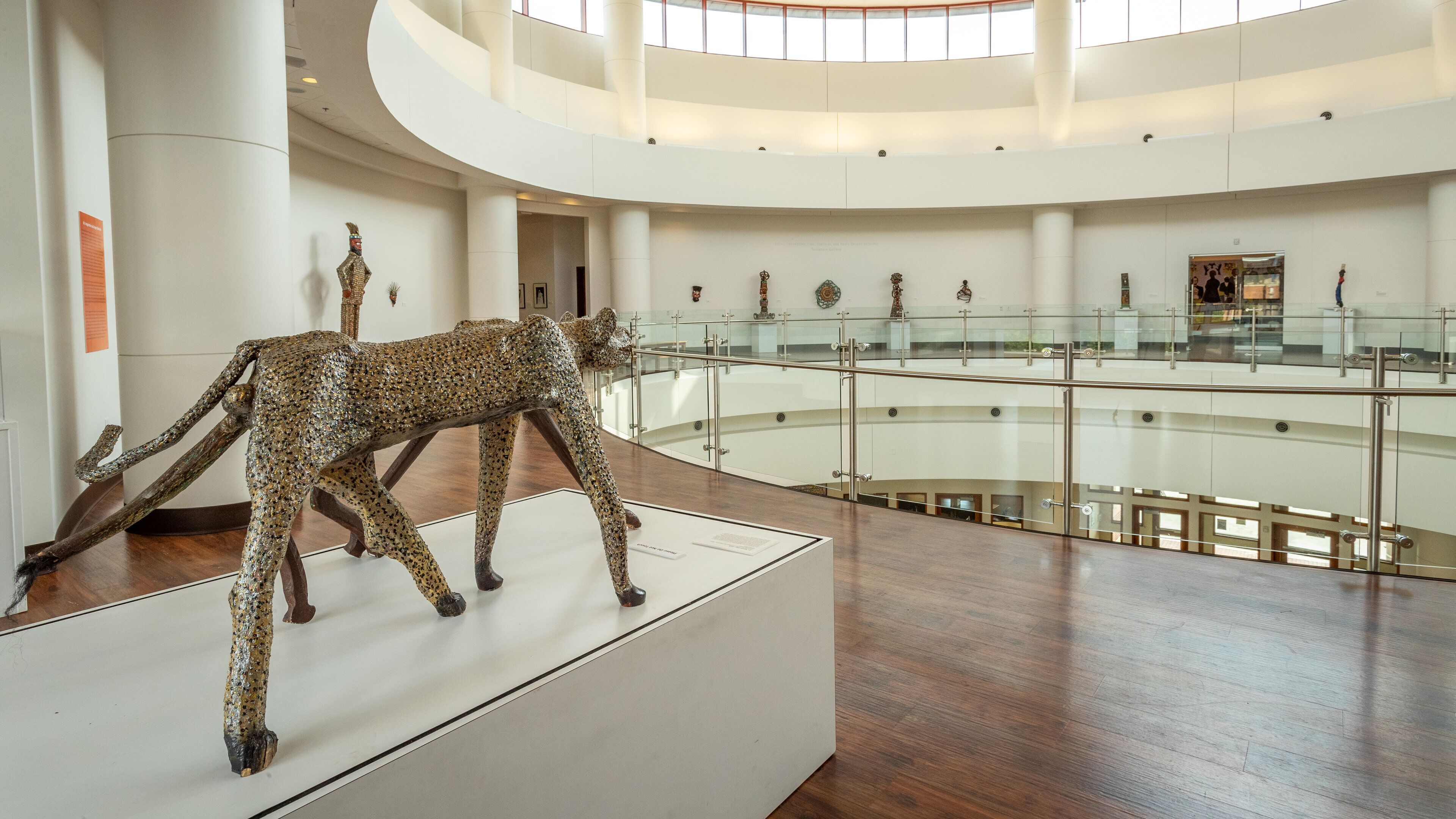 A modern building with a glass railing and a sculpture of a leopard.