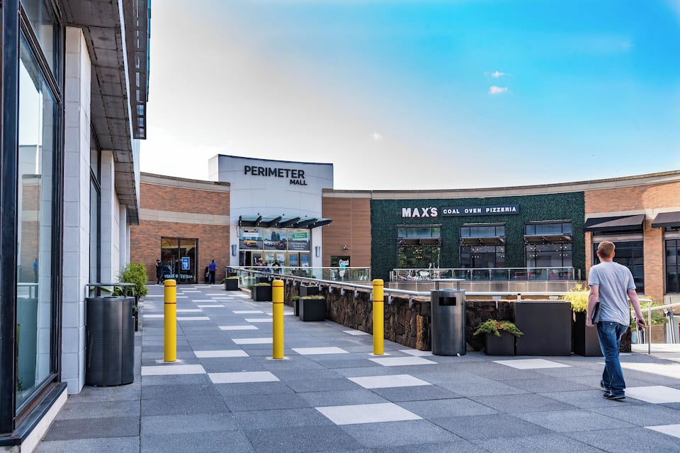 Uma área comercial com um anúncio para o Perimeter Mall e uma pizzaria chamada Max's Coal Oven Pizzeria.