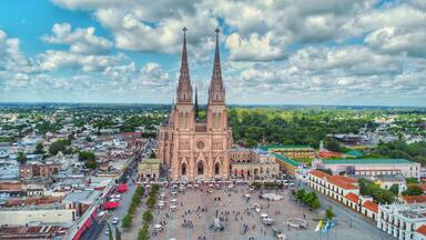 A cathedral with two tall spires, surrounded by a plaza with people and trees.