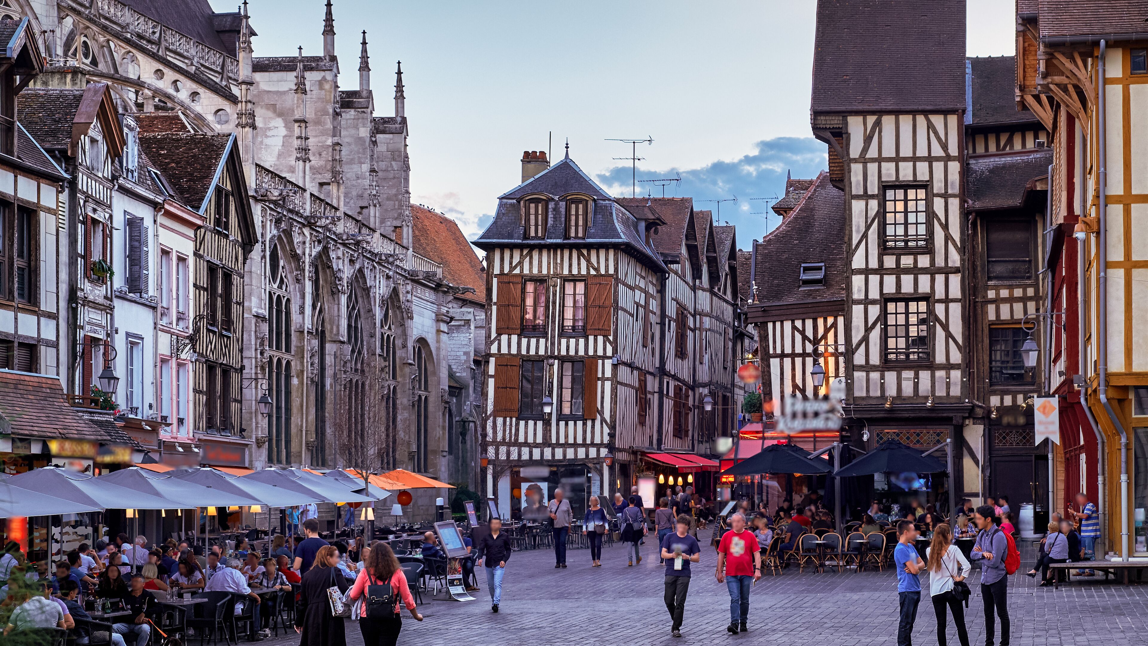 A cobblestone street lined with historic half-timbered buildings and outdoor cafes.