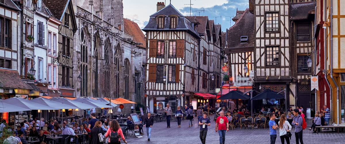 A cobblestone street lined with historic half-timbered buildings and outdoor cafes.