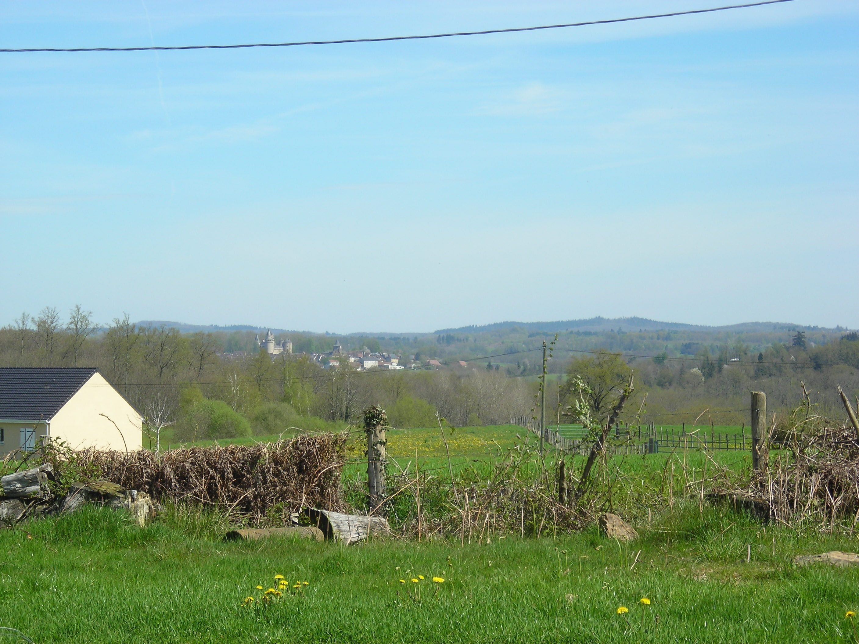 A rural landscape with a house, a stone wall, and a distant castle.