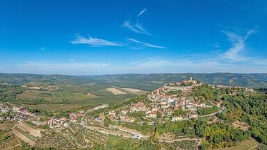 A mountainous landscape with a village nestled in the valley, surrounded by fields and forests.