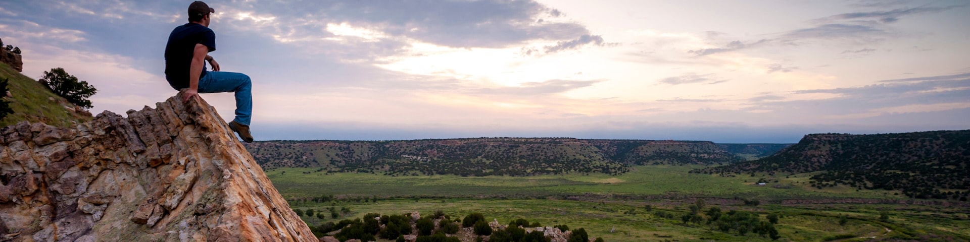 A man looking out over a canyon with a river running through. Picketwire Canyon, Southeast Colorado, USA.