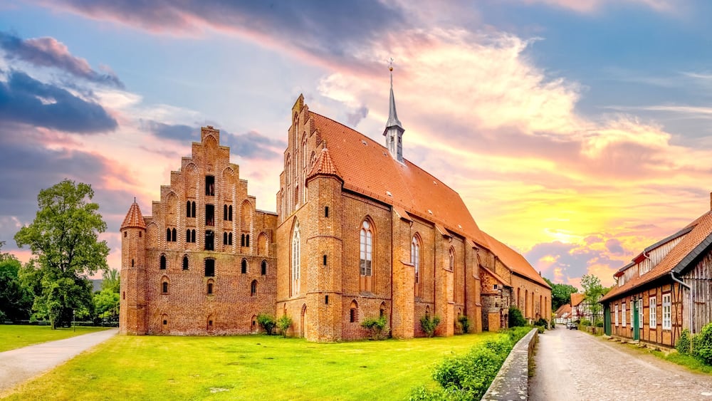 A historic church with a tall spire, surrounded by a well-maintained lawn and a cobblestone street.