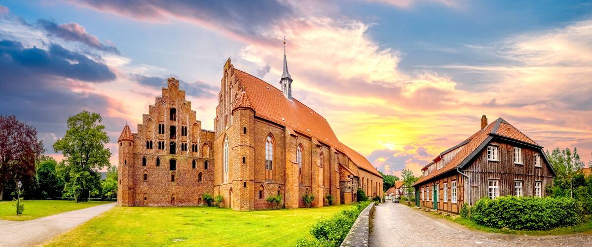 A historic church with a tall spire, surrounded by a well-maintained lawn and a cobblestone street.
