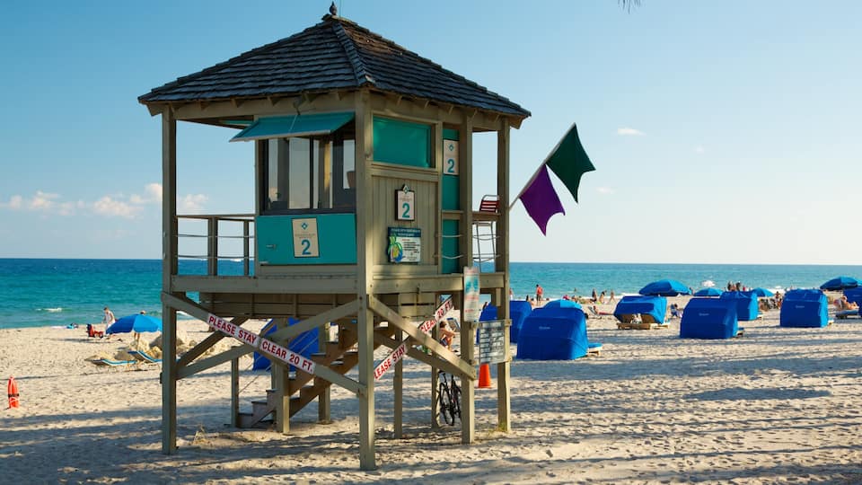 A lifeguard tower on a beach with blue umbrellas and beach chairs.