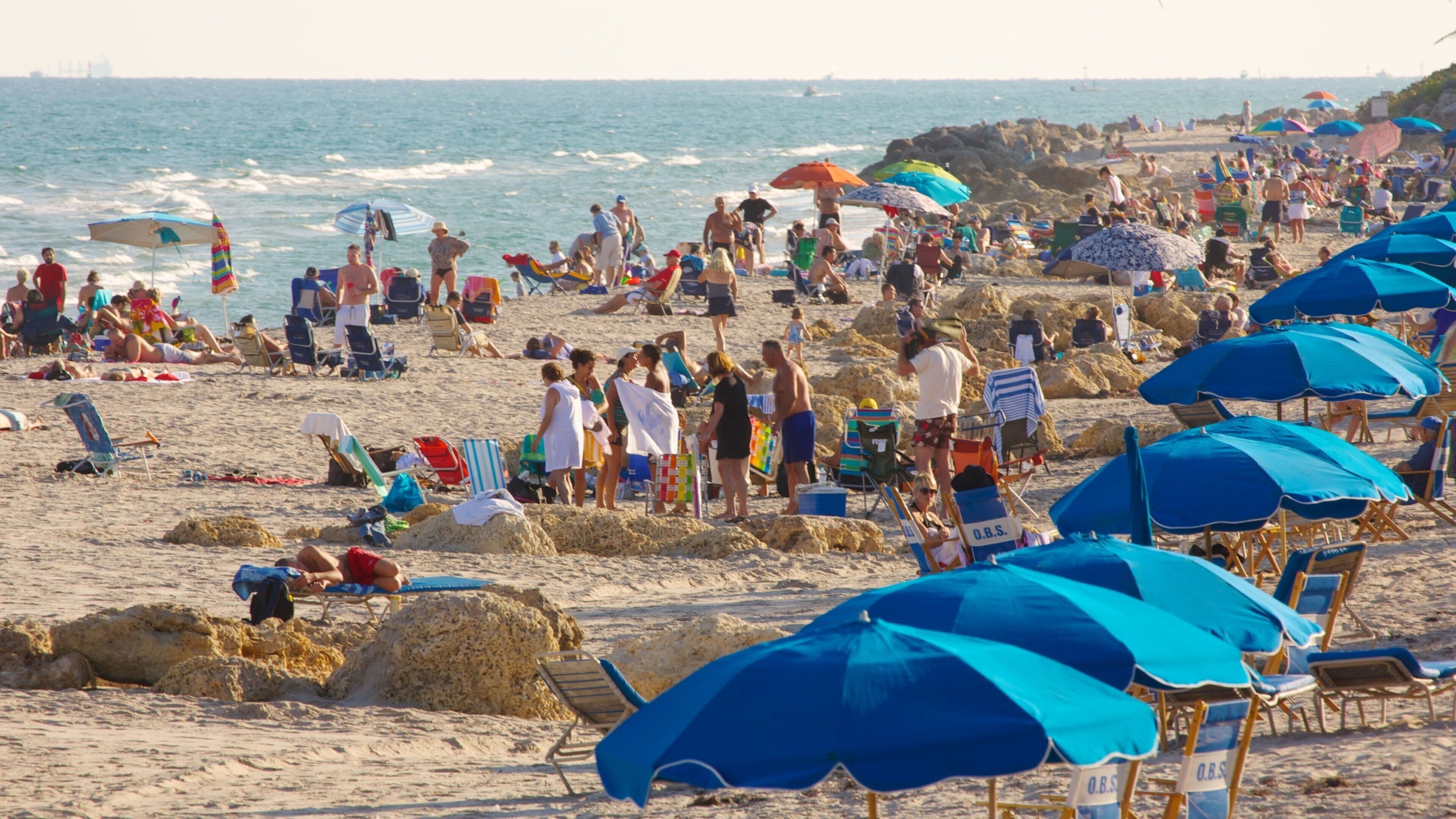 Beautiful day at Deerfield Beach Pier with families enjoying the sand and surf in Florida under colorful umbrellas