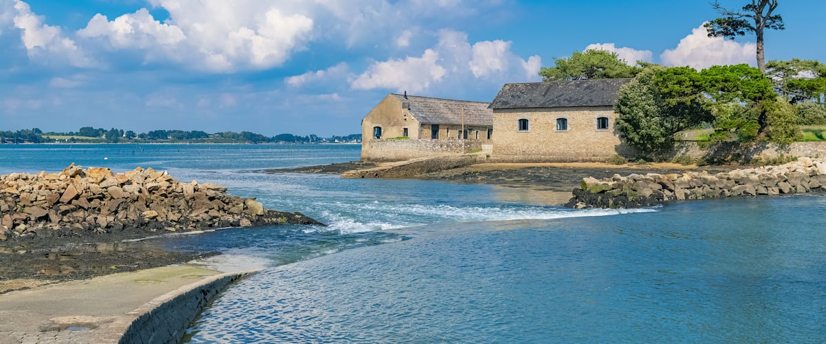 A coastal stone building by a calm sea with clear skies.