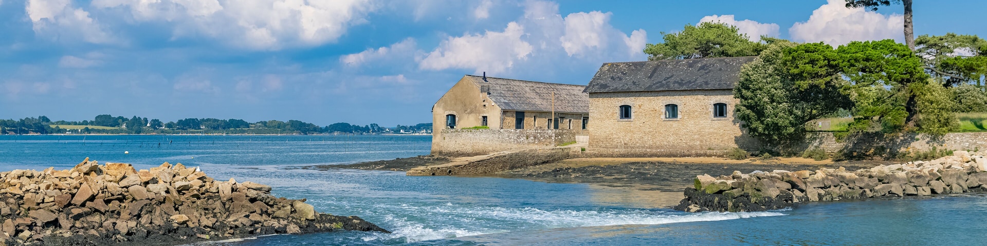 A coastal stone building by a calm sea with clear skies.