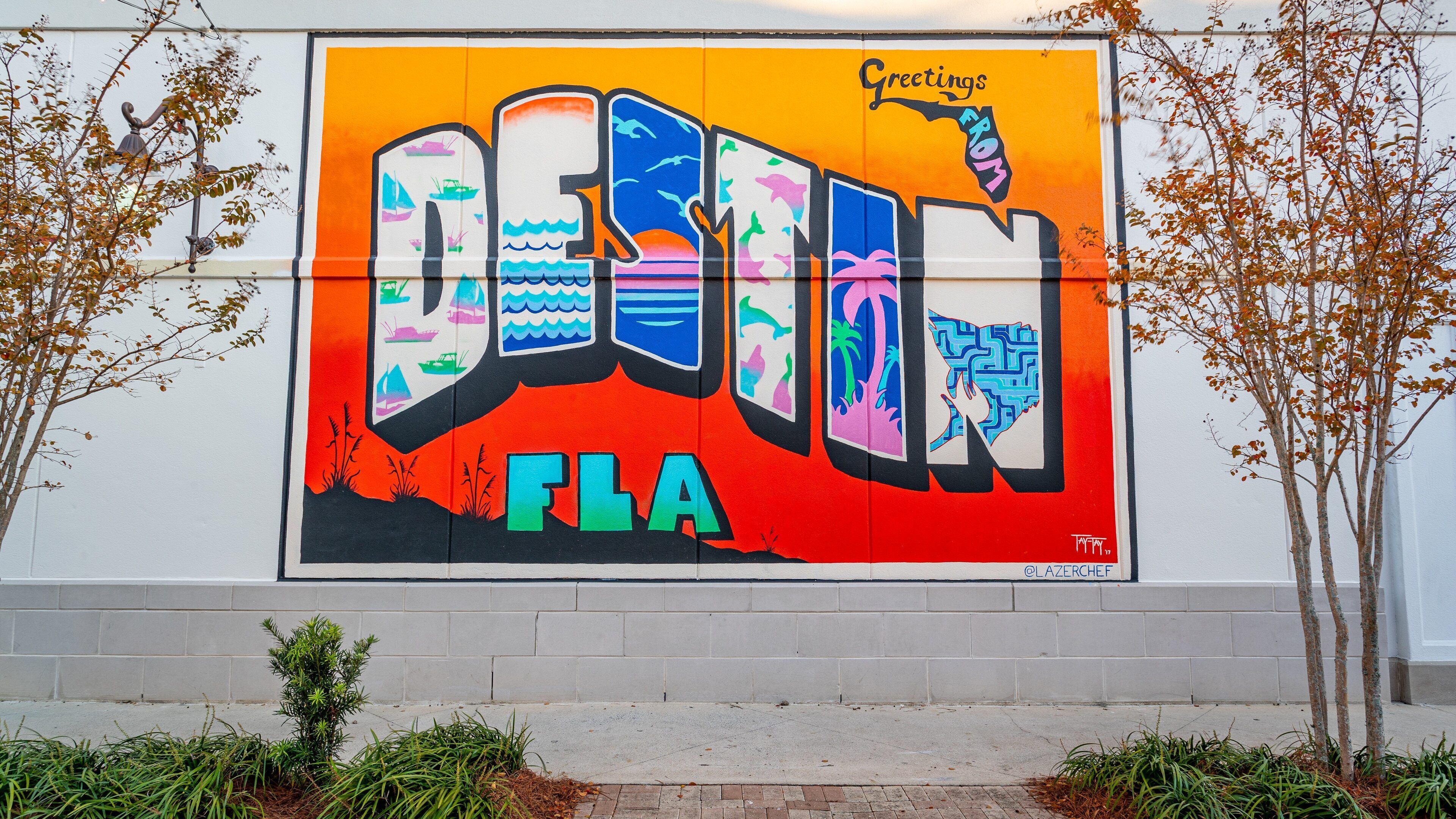 A colorful mural with the word "DESIGN" and "FLA" on a white wall.