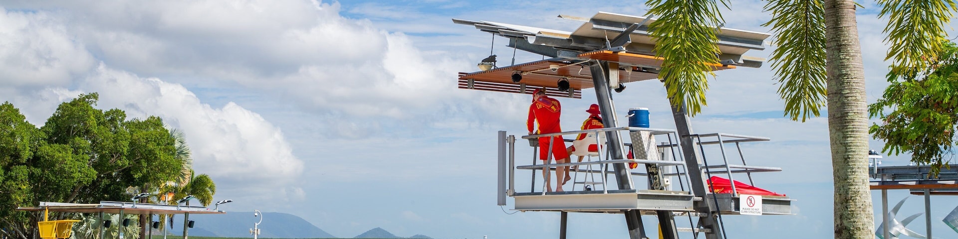 Una playa con una torre de salvavidas, palmeras y una piscina.