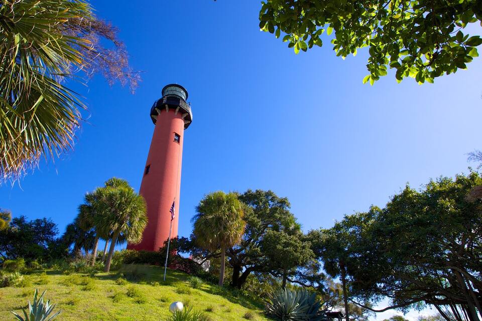 Un phare rouge, entouré d’une végétation luxuriante et de palmiers.