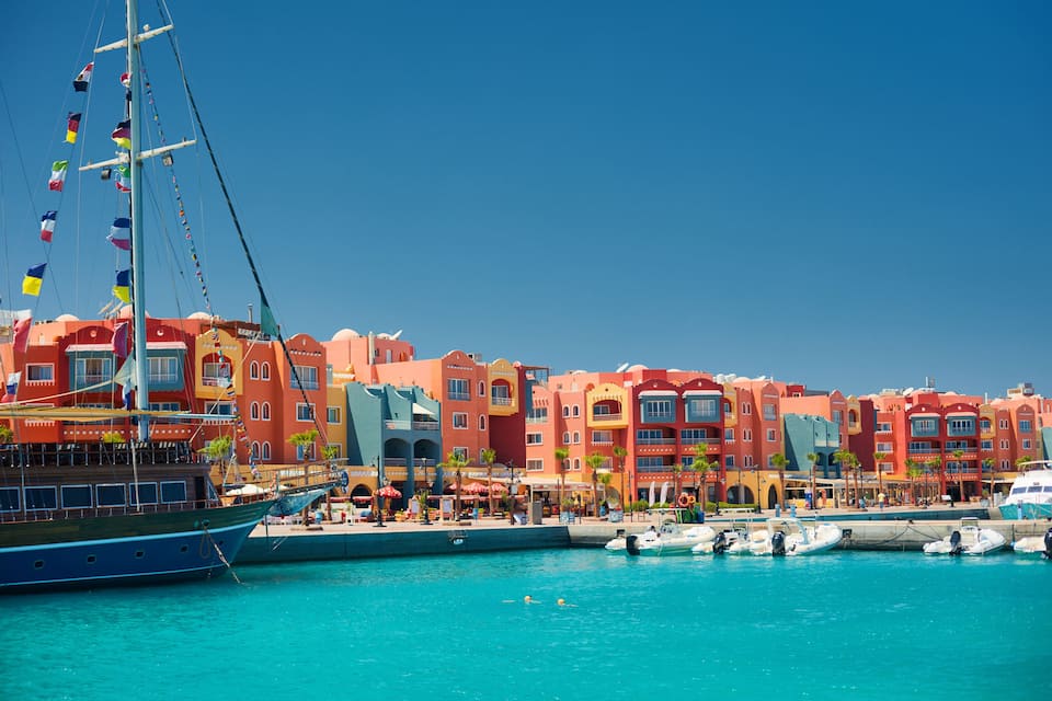 A harbor with colorful buildings, a large boat, and several smaller boats docked.