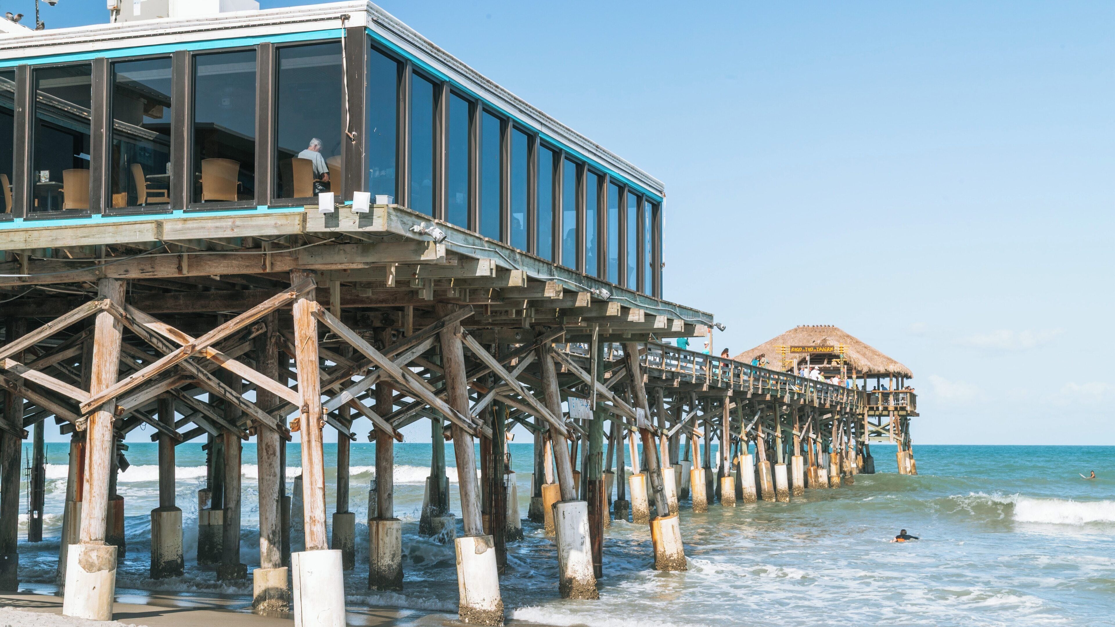 Cocoa Beach Pier stands tall against the tranquil ocean waves in Avon By The Sea, Florida, creating a perfect spot for relaxation and coastal enjoyment