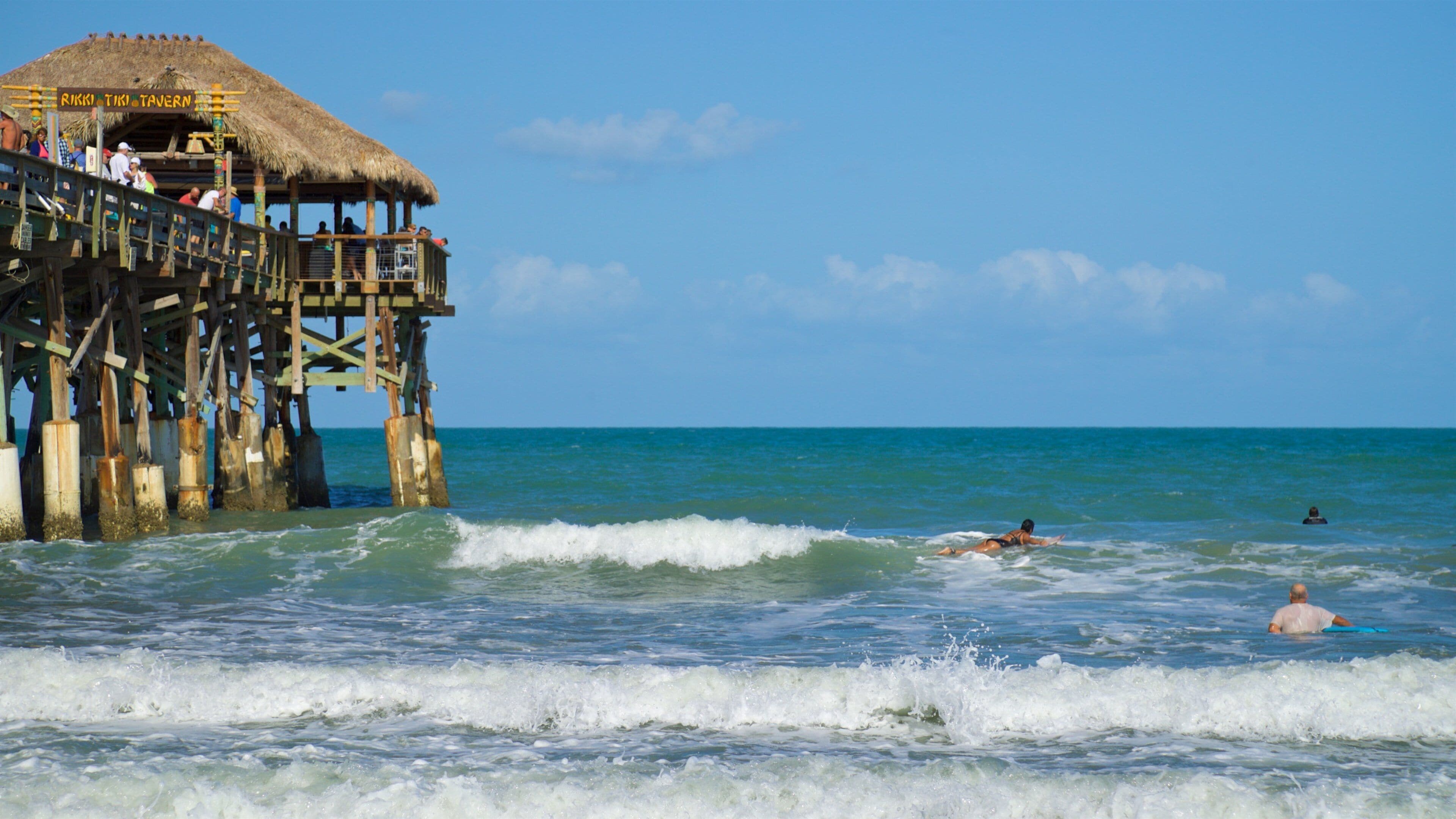 Cocoa Beach Pier which includes general coastal views and swimming as well as a small group of people