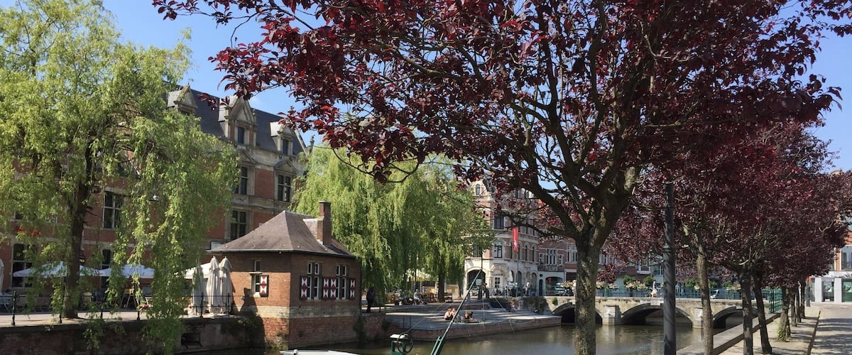 A canal with a small boat, a bridge, and buildings along the water.