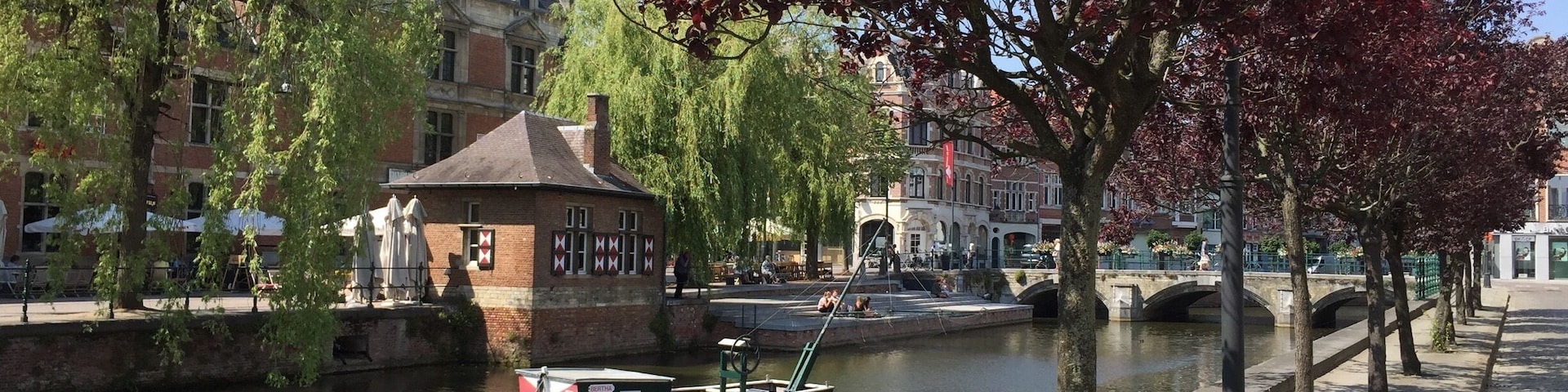 Un canal con un barco pequeño, un puente y edificios a lo largo del agua.
