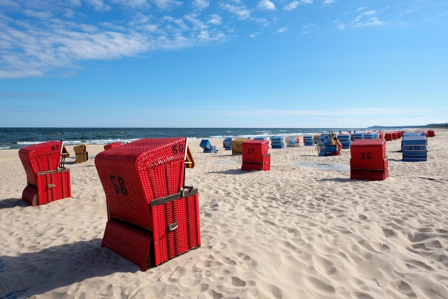 A beach with red and blue beach chairs and numbered storage boxes.