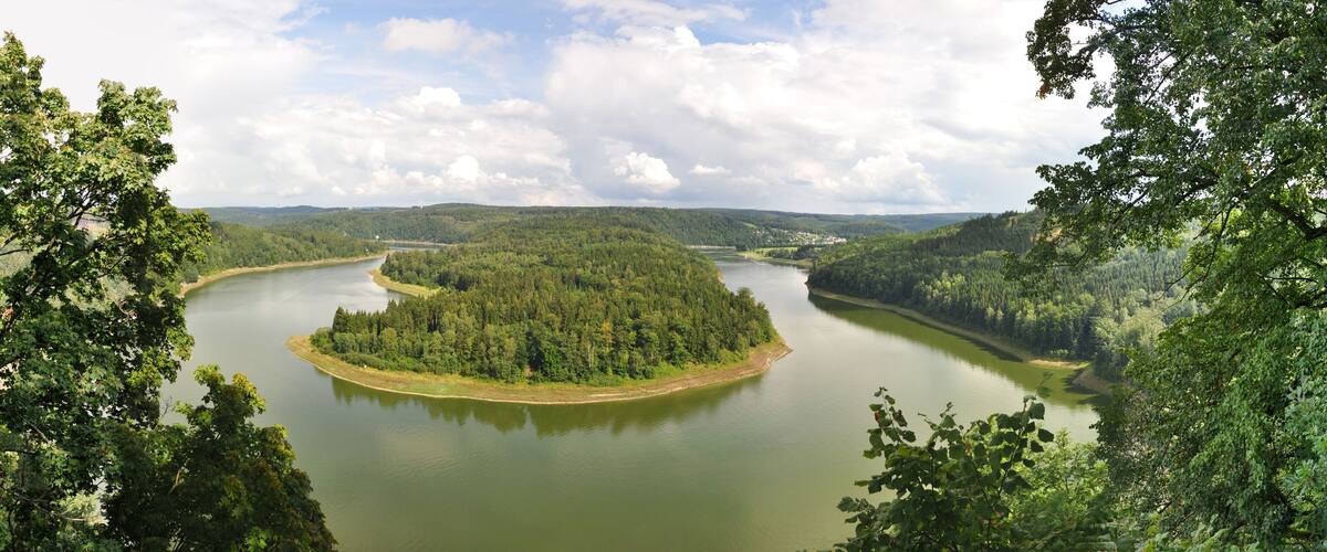 A river winding through a forested valley with a small island in the center.