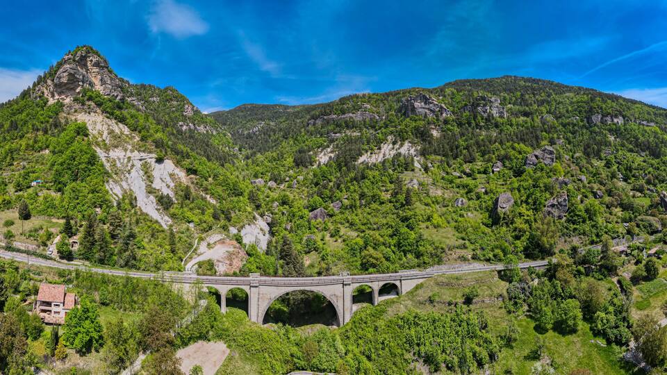 A mountainous landscape with a bridge and a house.