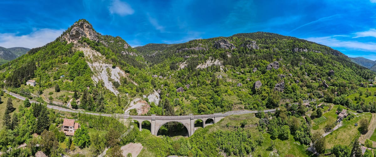 A mountainous landscape with a bridge and a house.