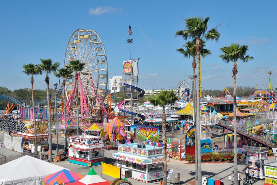A vibrant amusement park with a large Ferris wheel, various rides, and colorful food stalls.