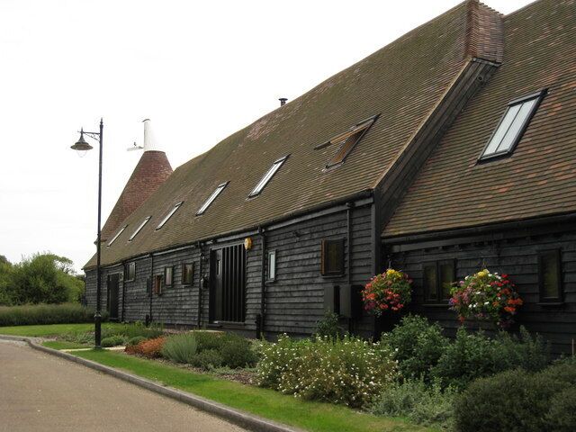A traditional wooden building with a sloped roof, a chimney, and flower boxes on the windows.