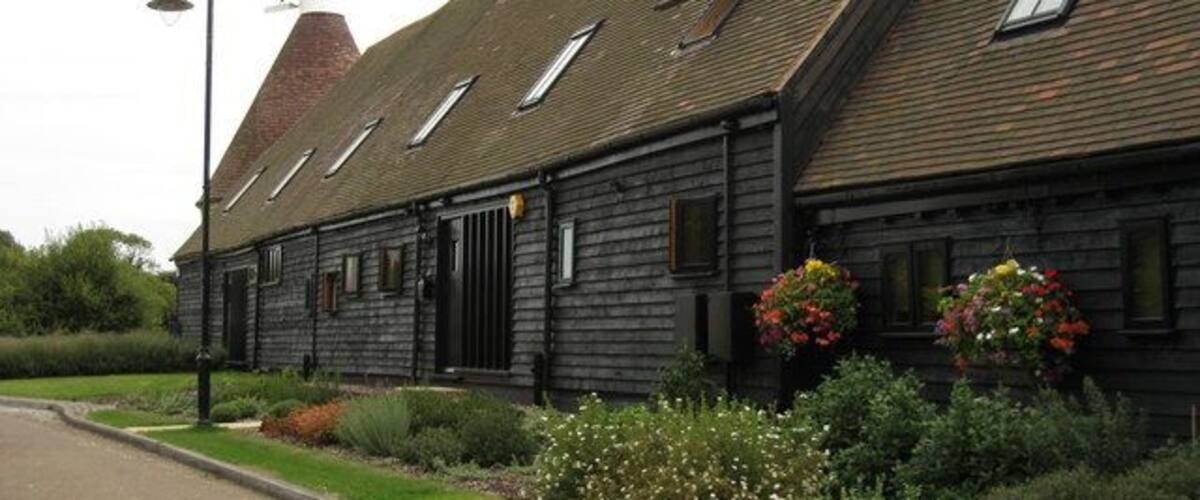 A traditional wooden building with a sloped roof, a chimney, and flower boxes on the windows.