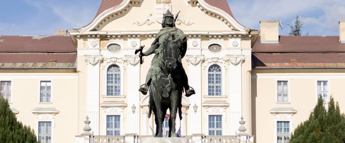 A statue of a man on horseback in front of a building with ornate architecture.