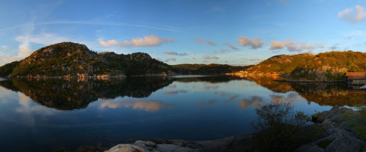 A calm lake with reflections of hills and a clear sky.