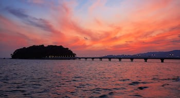 A sunset over a body of water with a bridge and an island in the distance.