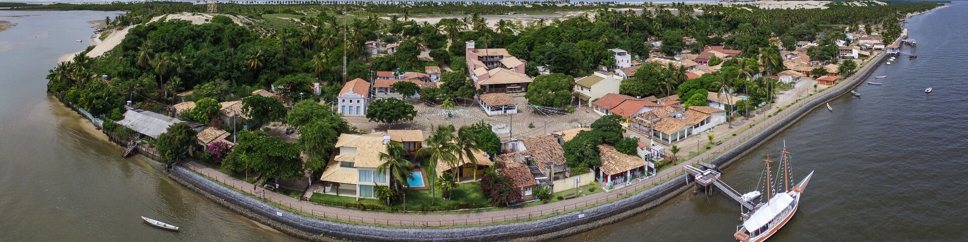 Vista aérea de un pueblo costero con playa, casas y un puerto deportivo.