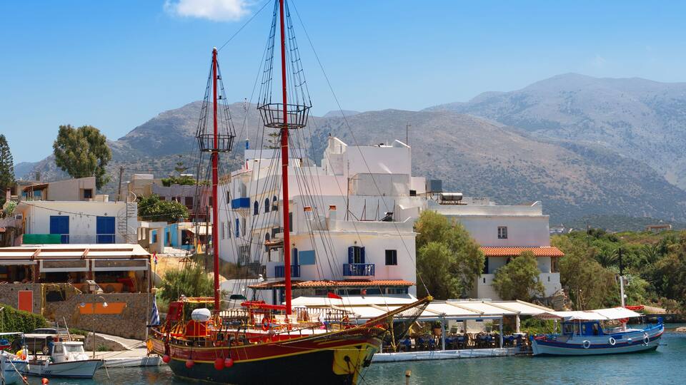 A harbor with boats, a large sailboat, and buildings with blue and white facades.