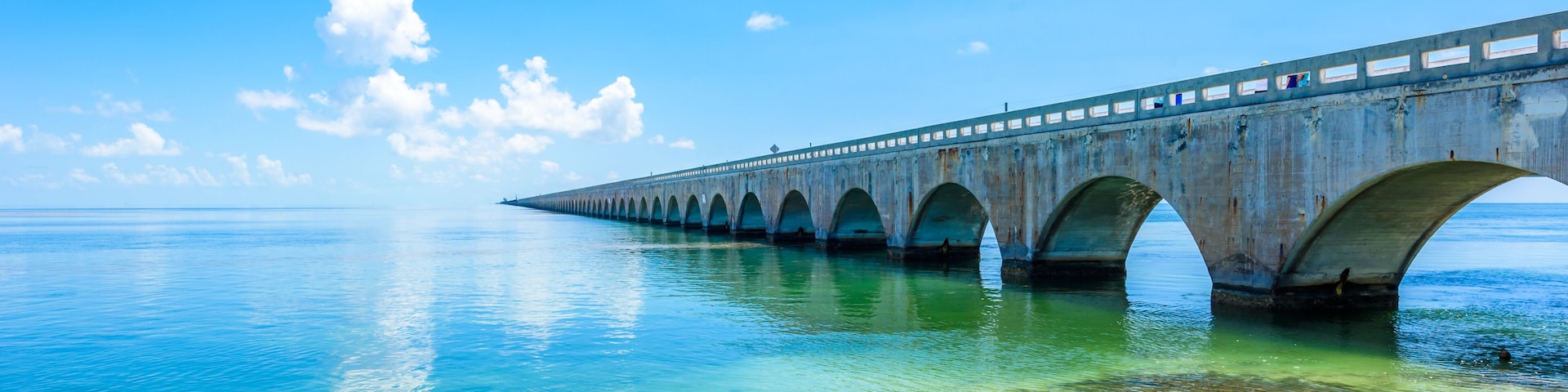 Un puente largo sobre aguas tranquilas y cristalinas, bajo un cielo despejado.