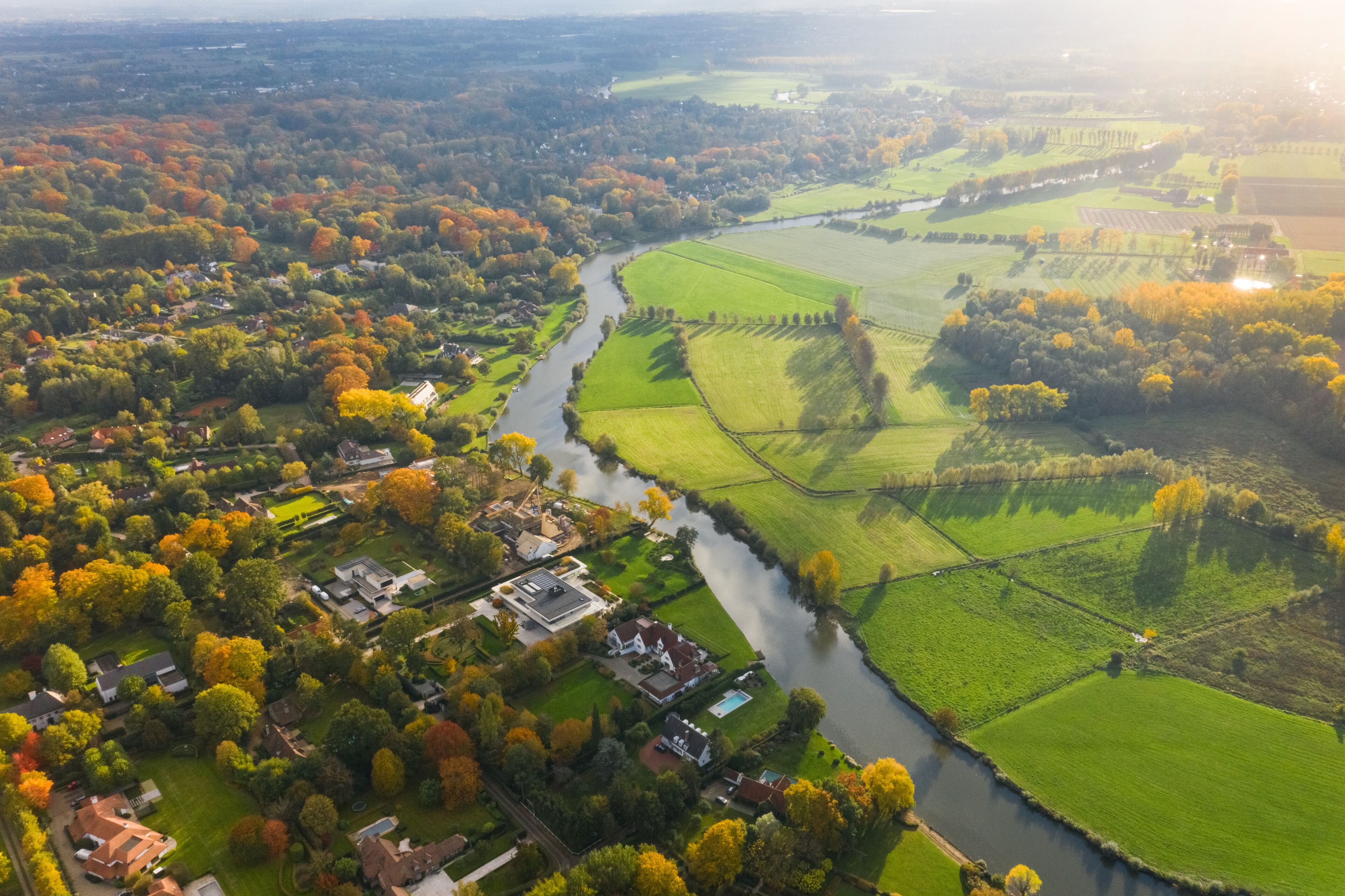 Aerial view of houses with view on agricultural land in autumn, in Belgium.