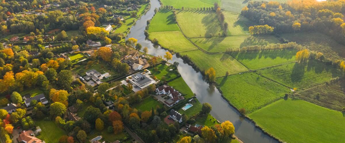 An aerial view of a river winding through a rural landscape with fields and houses.