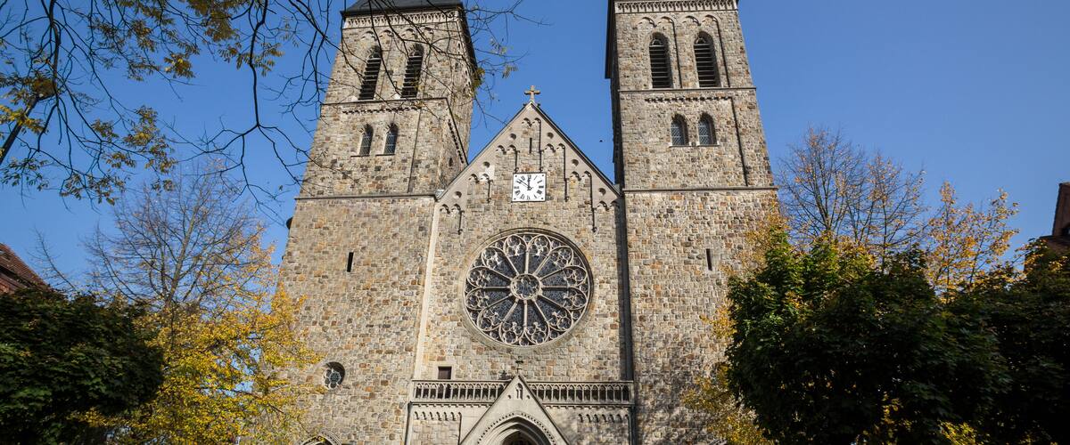 A historic stone church with twin towers and a large rose window.