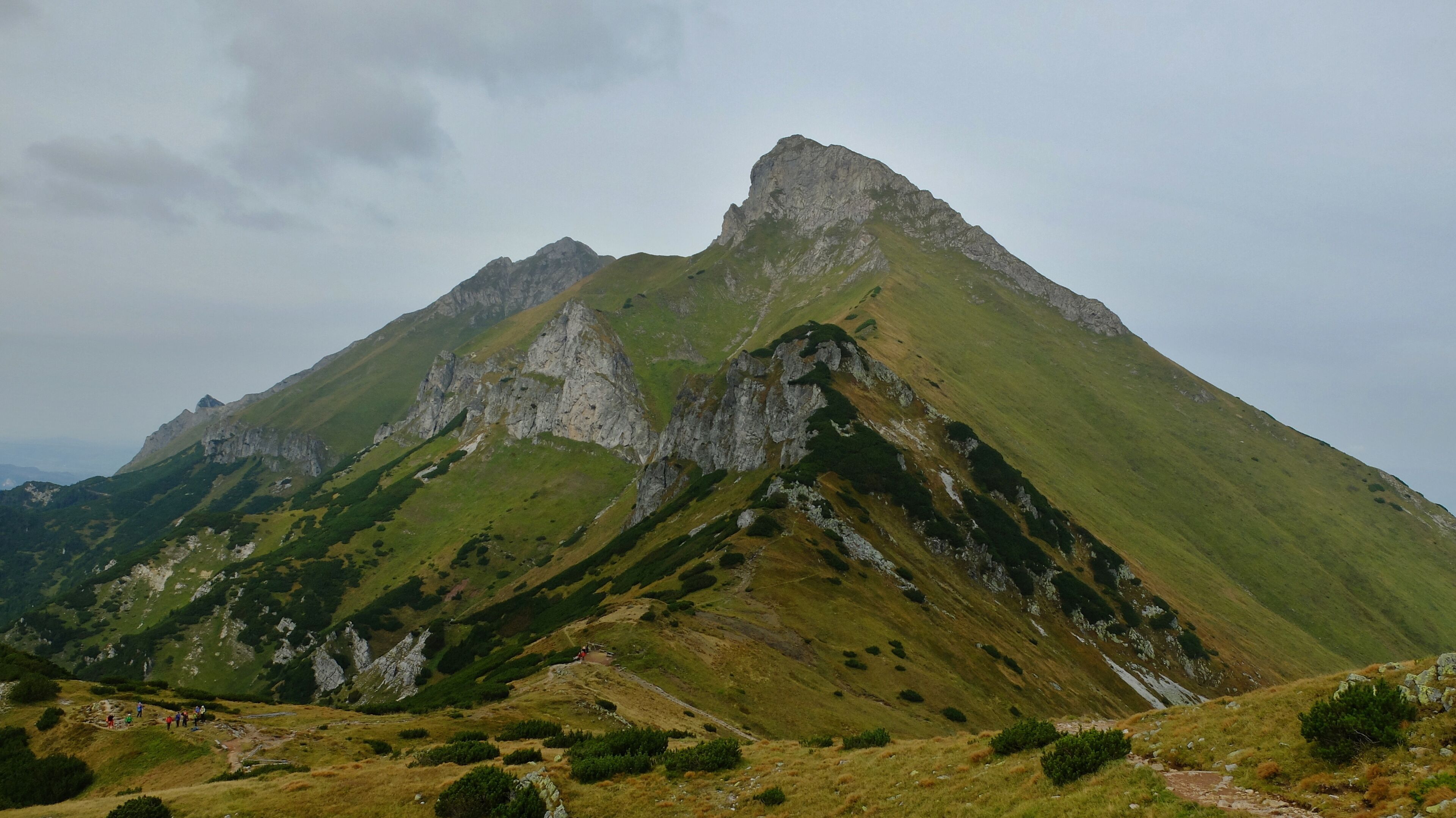 A mountain with a prominent peak and surrounding green slopes.