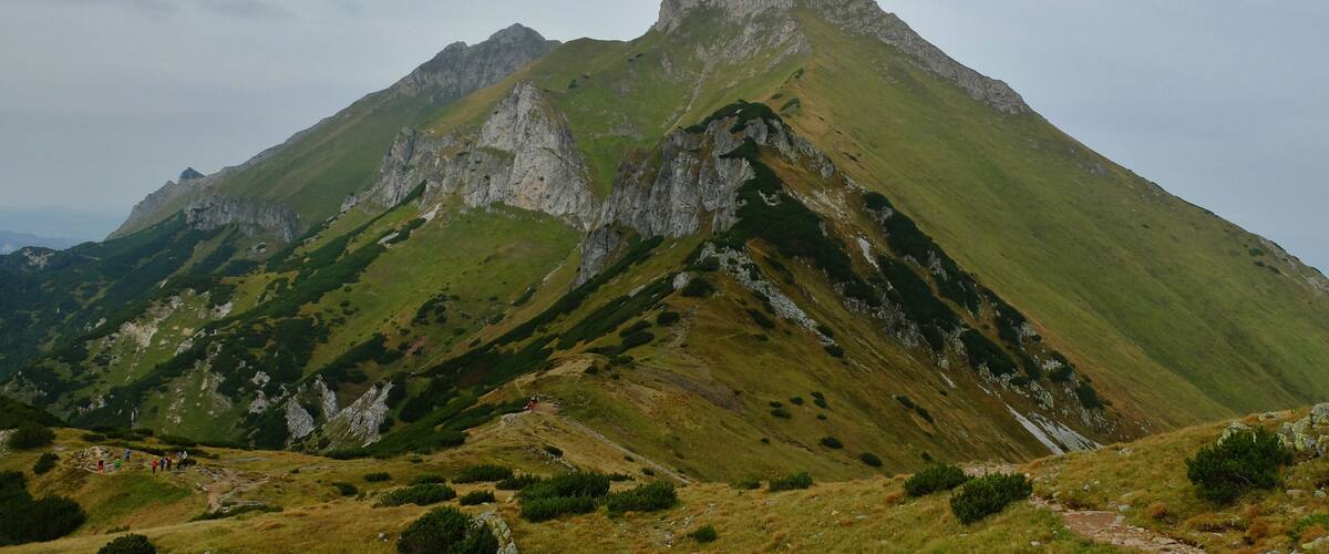 A mountain with a prominent peak and surrounding green slopes.
