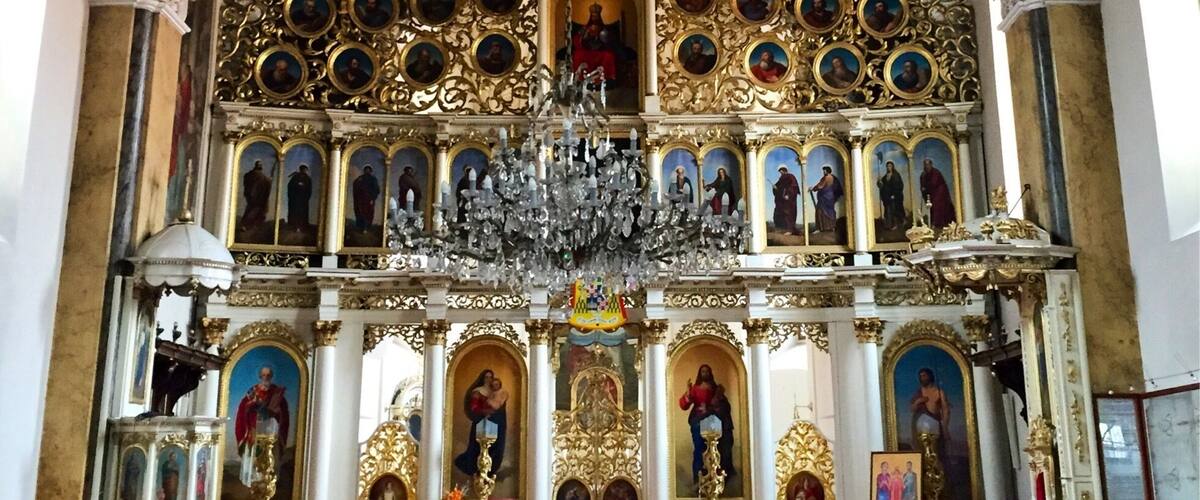 An ornate church interior with a high ceiling, a central altar, and rows of pews.