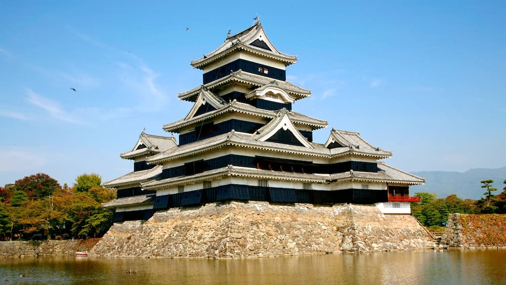 A traditional Japanese castle with multiple tiers, a stone base, and a surrounding moat.